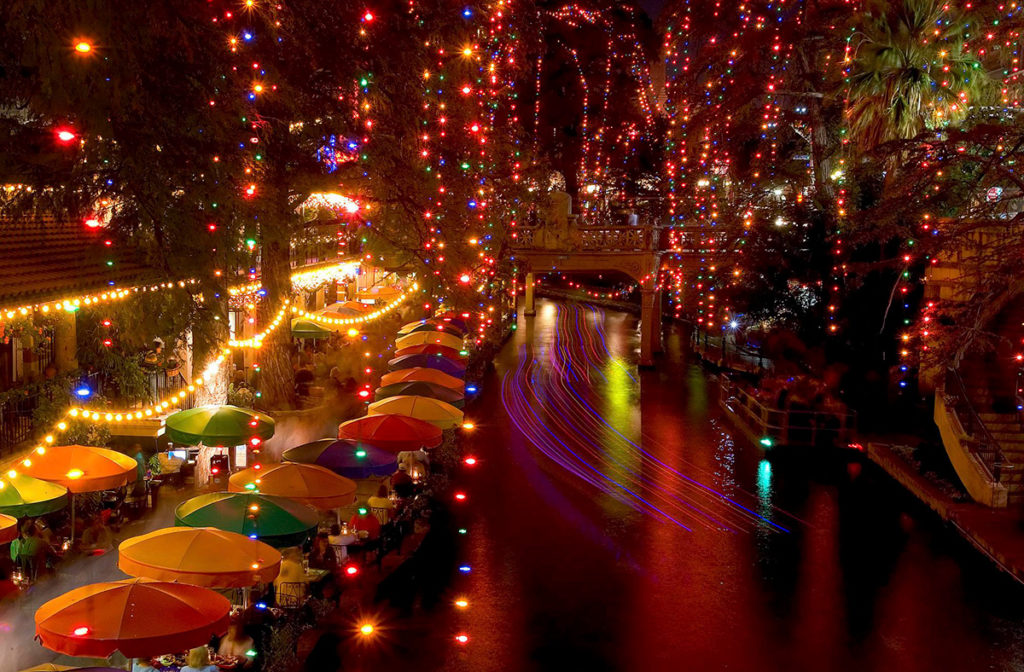 Lights drape from trees and cross the San Antonio River during the holidays.