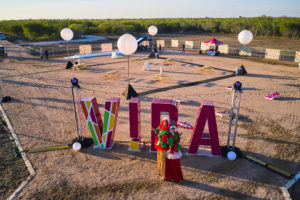 a large VIDA sign outdoors with stilted performers posing in front, at VIDA San Antonio near Texas A&M - San Antonio