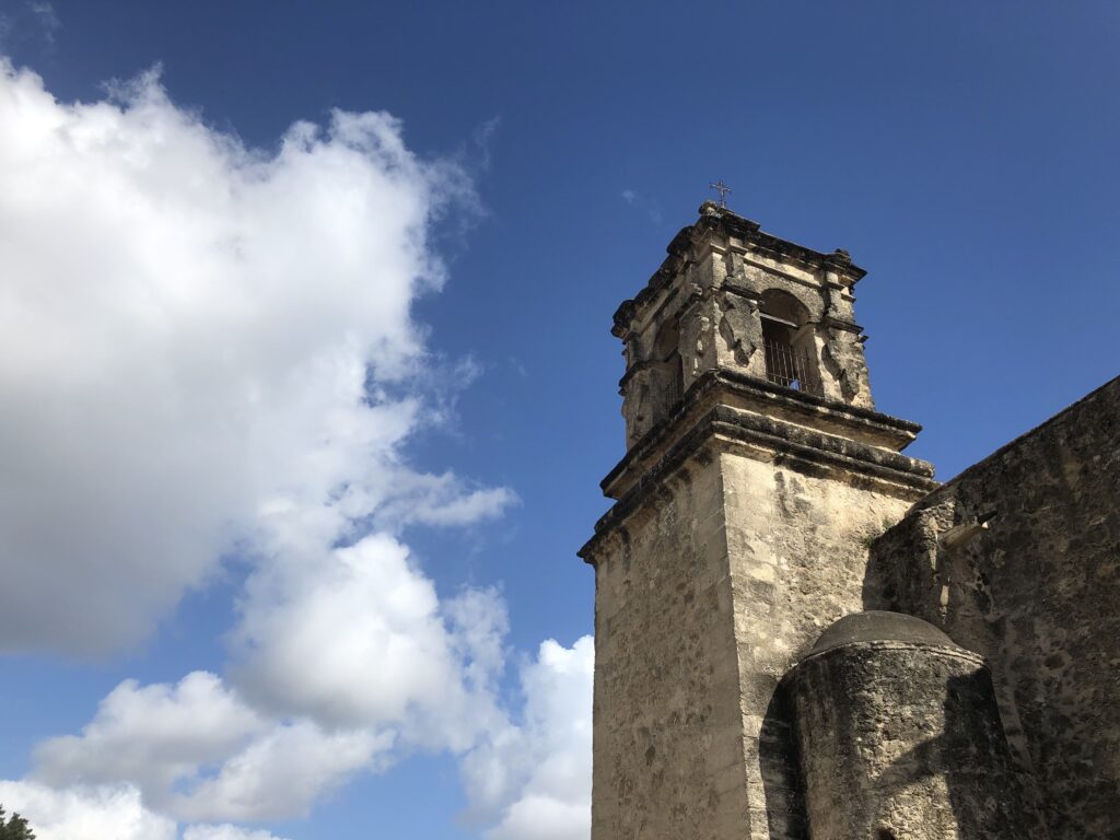 An upward view at San Jose Bell Tower with a blue sky and clouds in the sky