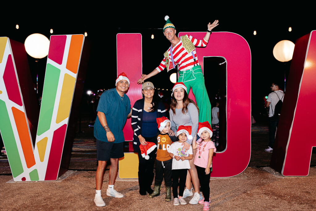 Family poses for a holiday photo in front of a large VIDA sign. 