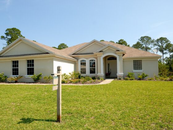 a stock image of a home with a green lawn and a "for sale" sign