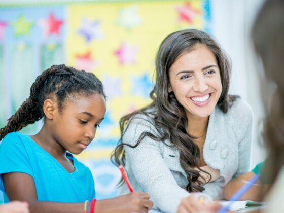 A teacher smiles next to a student
