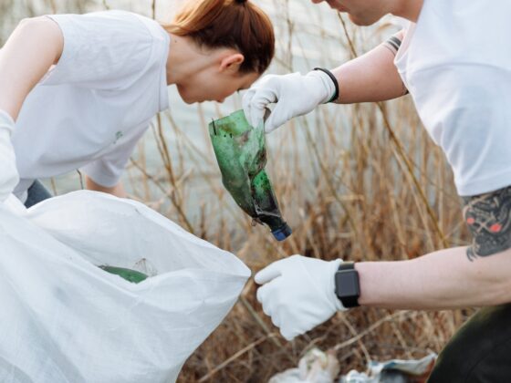 two people picking up trash by a river