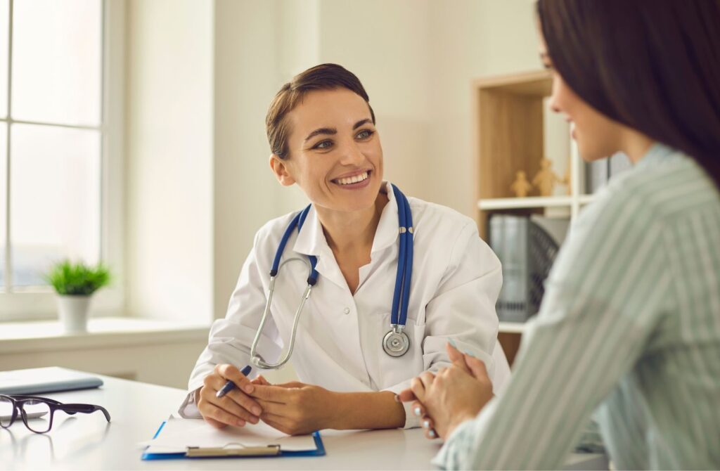 A doctor speaks to a patient in her office with a smile.