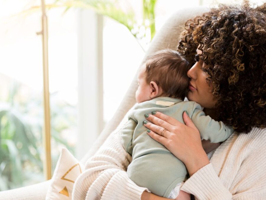 A new mother looks out the window with her baby in San Antonio