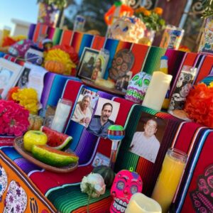 Candles, photos of loved ones, and fruit on an ofrenda