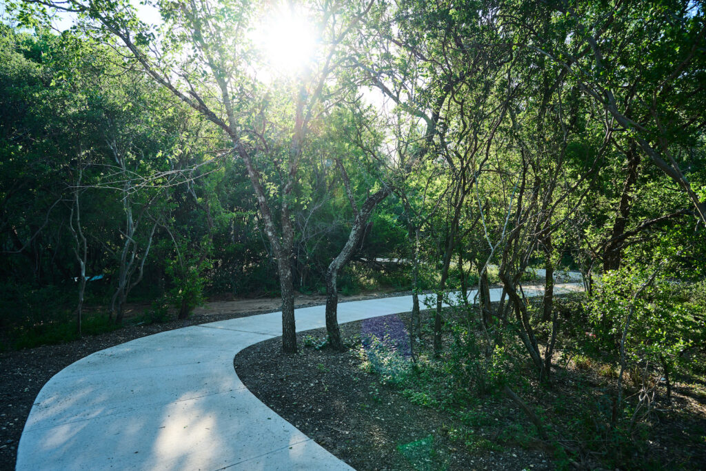 A shadowed path amidst trees on the Madla Greenway in San Antonio