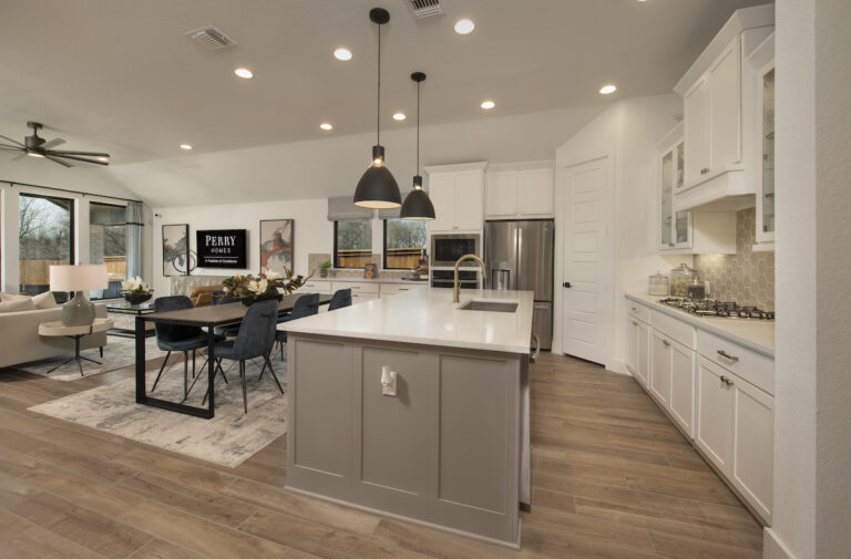 A neutral interior of a Perry Homes Model Home, the Kitchen is renovated and modern with recessed lighting