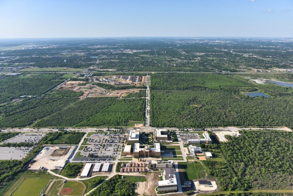 A blue sky with Texas A&M-San Antonio in the foreground and the VIDA San Antonio community in the distance.