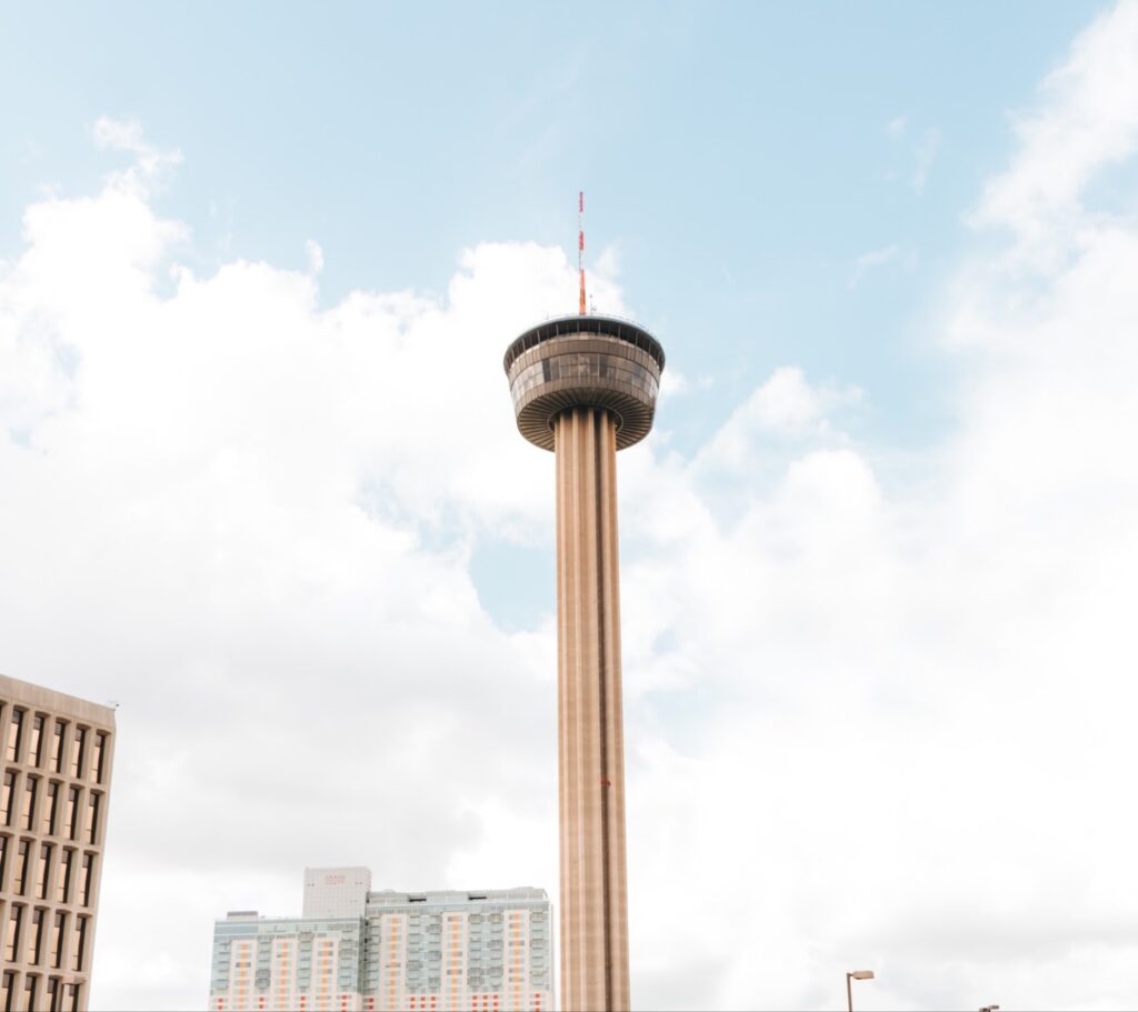 The Tower of the Americas stands tall against a pale blue Texas sky 