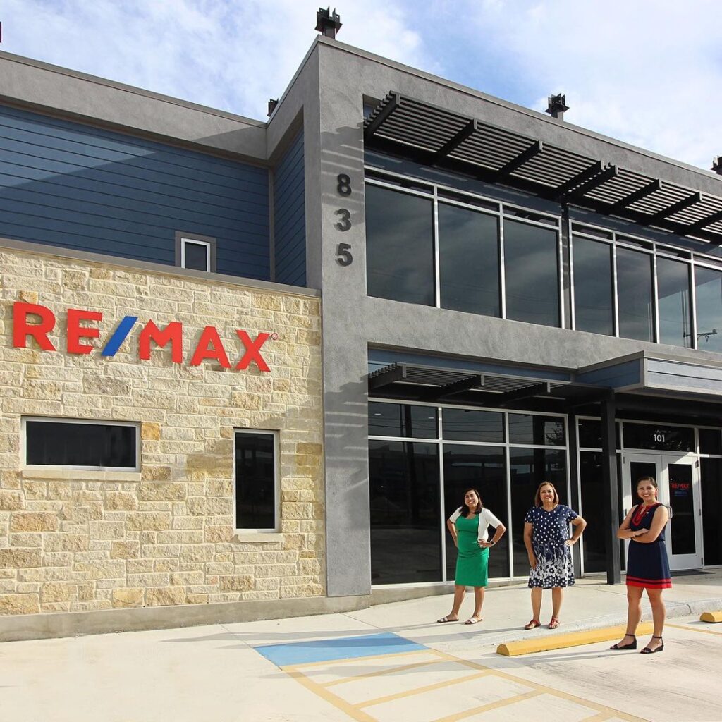 Sara Briseño Gerrish and two coworkers stand outside of the Re/Max building.