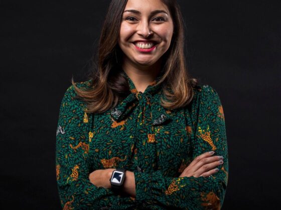 Sara Briseño Gerrish poses in a green blouse with a smile and her arms crossed for a portrait