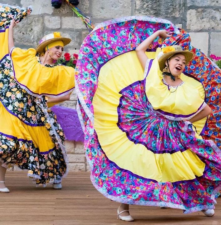 folklorico dancers perform in large colorful dresses