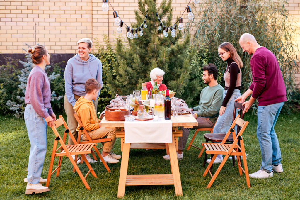 A multi-generational family sits down for an outside picnic meal