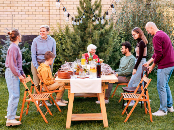 A multi-generational family sits down for an outside picnic meal