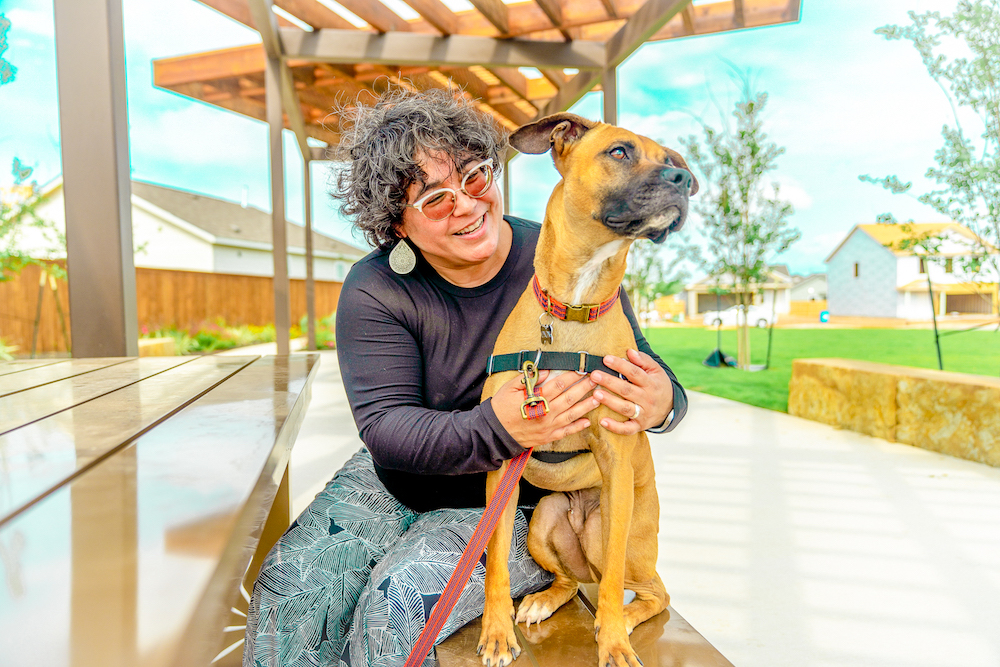 A visitor at Ana Park enjoys some sunshine with her dog.