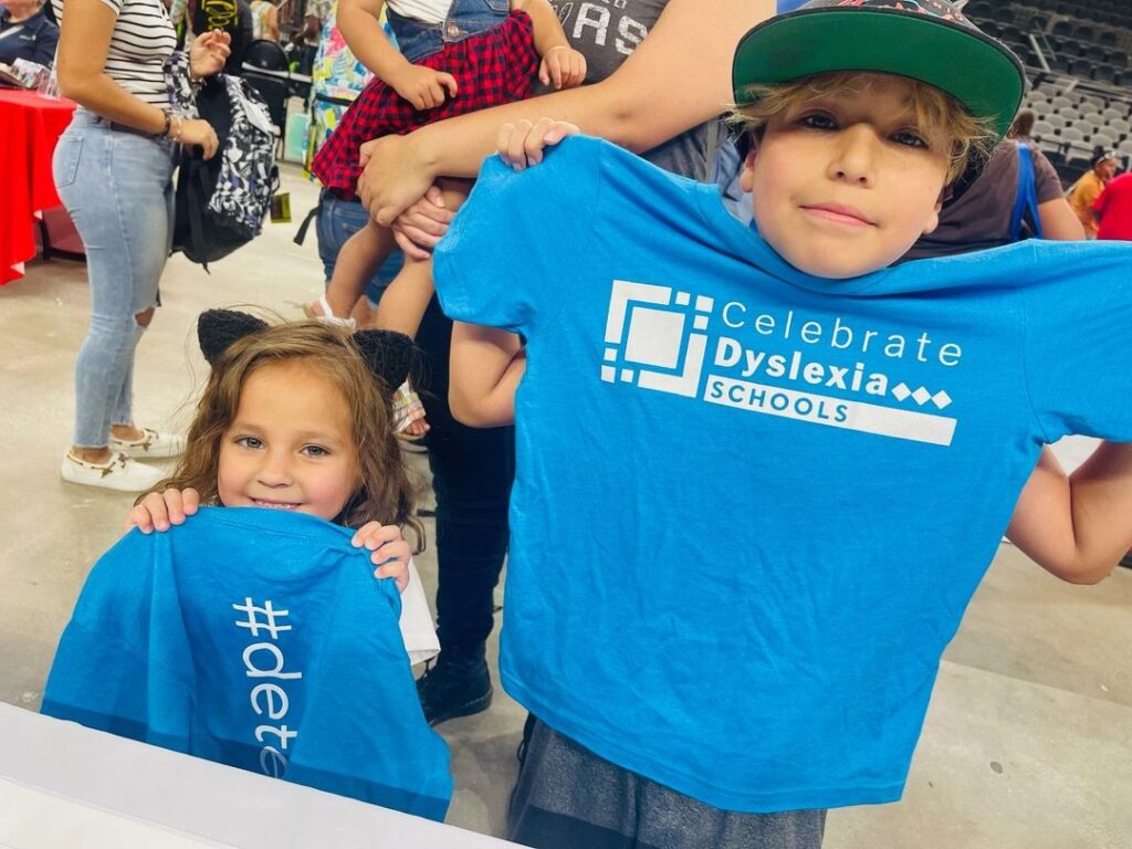 Children hold Celebrate Dyslexia Schools t -shirts and smile