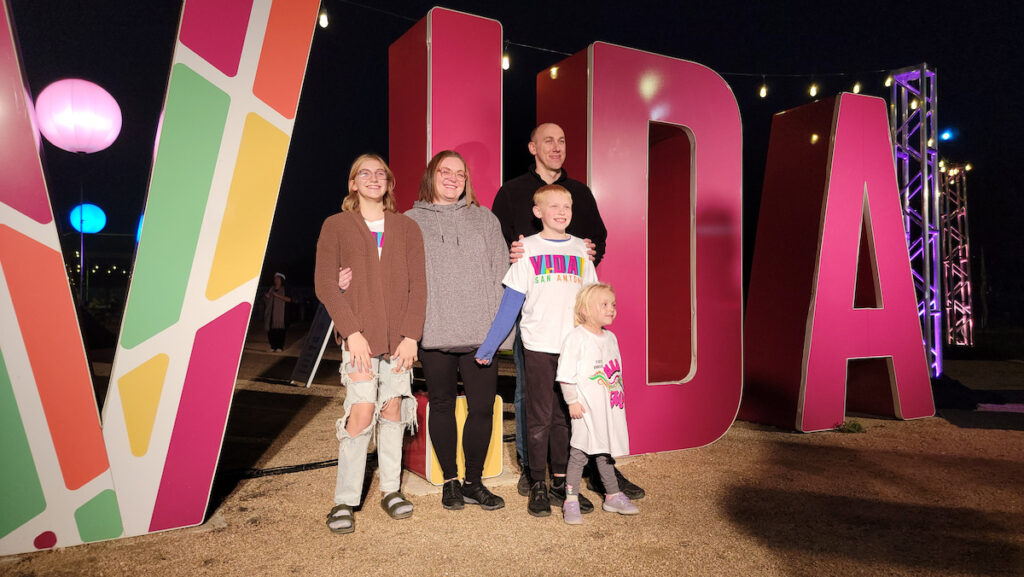 A family poses for a photo wearing VIDA t-shirts.
