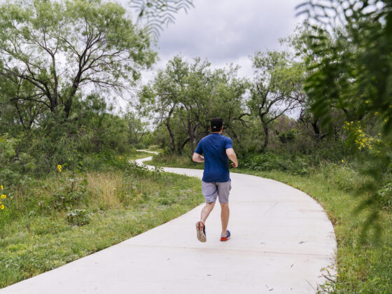 A man runs on a lush trail.