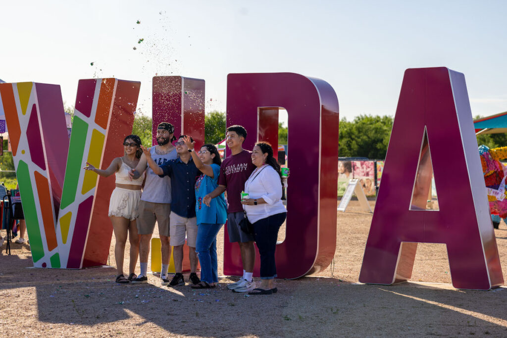 People gather to celebrate with confetti in front of the VIDA sign