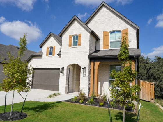 A white brick home with black and oak accents built by Perry Homes in the VIDA San Antonio neighborhood