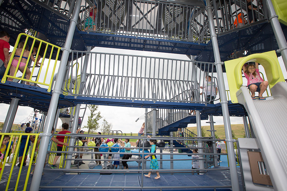 Children play on a multi level park structure with a slide