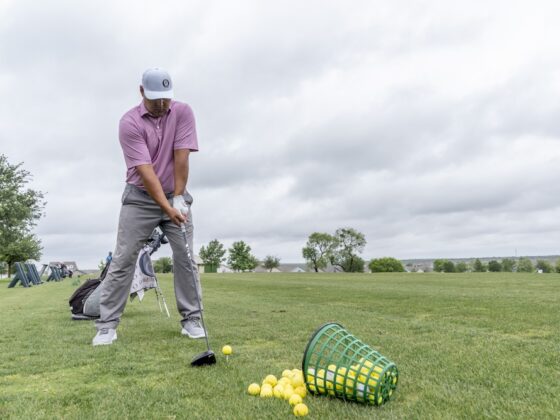 Ray Garza playing golf with a basket of golf balls nearby