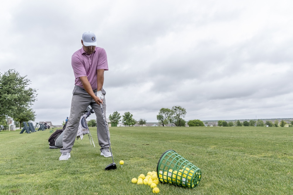 Ray Garza playing golf with a basket of golf balls nearby