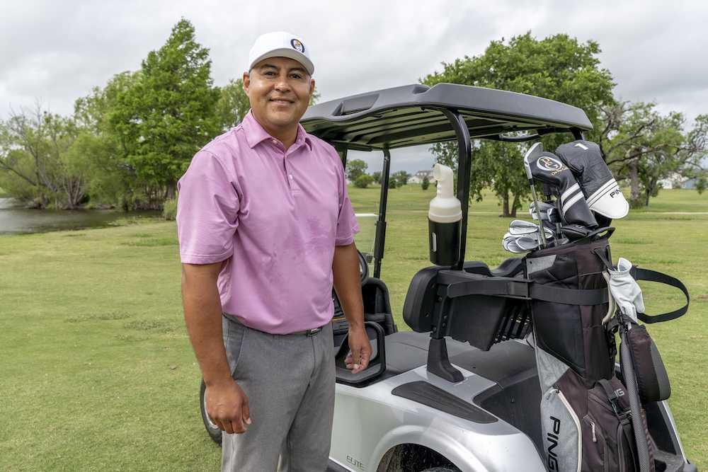 Ray Garza poses for a photo near a golf cart