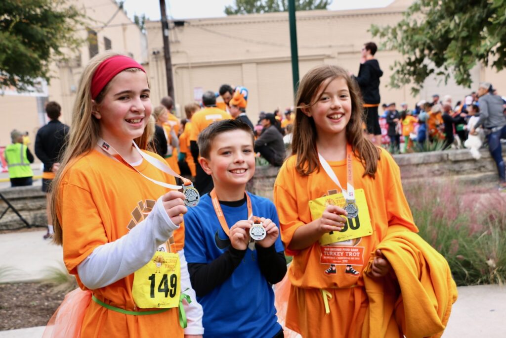 young kids hold up medals from a 5k
