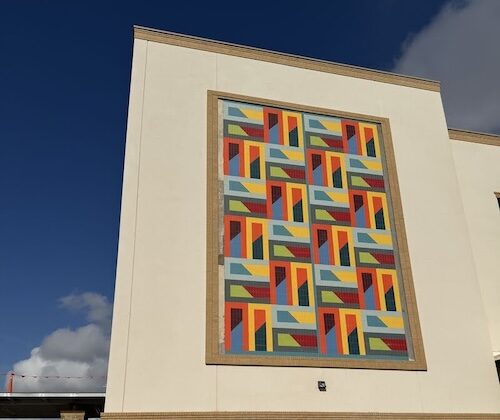 Colorful, geometric mural on the side of a newly built healthcare facility