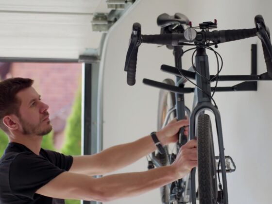A man lifts a bicycle up onto a bike rack located inside of a garage - Spring Clean Your Two-Car Garage and Make the Space Work for You