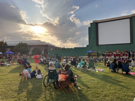 Mission Marquee Plaza in San Antonio - large group of people sitting in the grass in front of a large screen to watch an outdoor movie