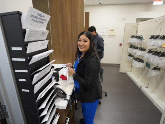 A woman smiles while bagging medication in the University Health Vida pharmacy