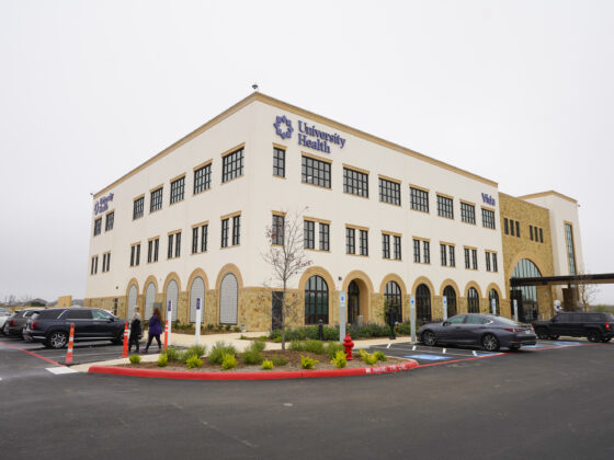 University Health Vida clinic building exterior showing a large white building with cars parked in a parking lot beside it