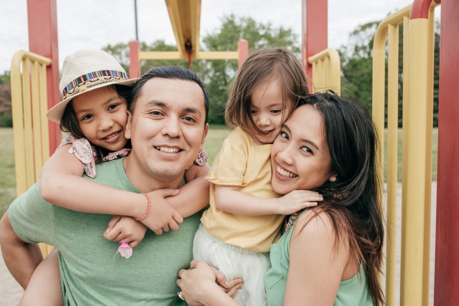 Smiling family with two children enjoying the outdoors at a park.