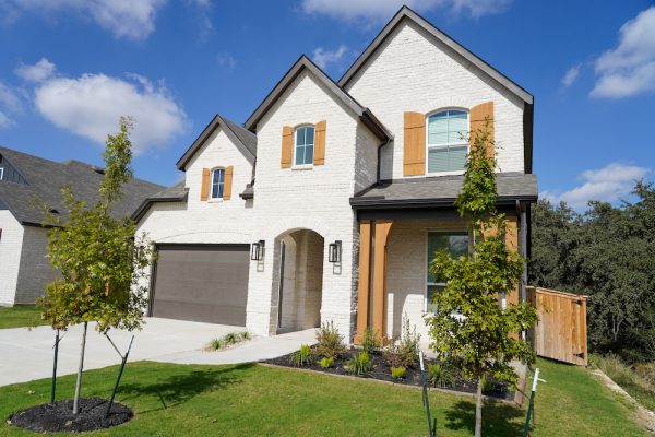 A white brick home with black and oak accents built by Perry Homes in the VIDA San Antonio neighborhood