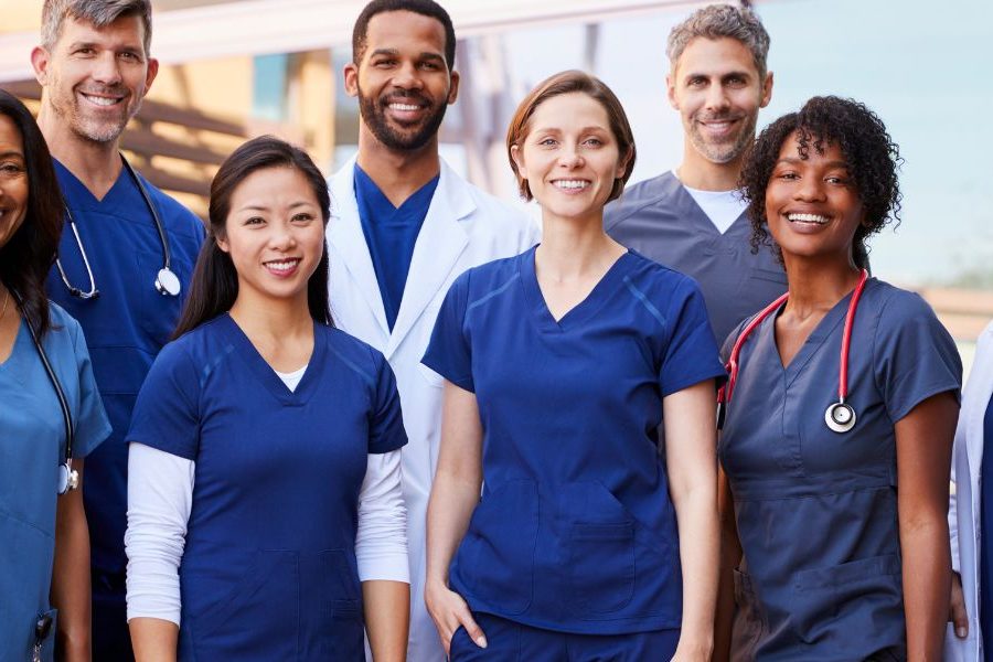 A group of health professionals poses for a photo in scrubs